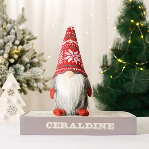 Christmas gnome doll with red knitted snowflake hat and white beard on a cozy background