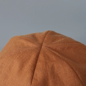 Detailed macro view of brown linen sun hat crown showing six-panel stitching and texture