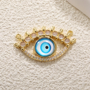 Gold Evil Eye pendant with blue zircon stones and clear crystals on textured background