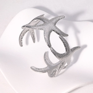 Polished silver starfish open bangle bracelet with detailed sea life texture on white background