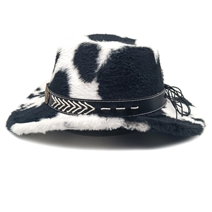 Detail of faux fur cow print cowboy hat featuring a black leather band and metal badge