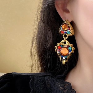 Close-up of vintage gold triangle earrings set with colorful orange and red gemstones