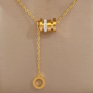 Gros plan d'un collier doré avec pendentif cylindrique serti de cristaux étincelants