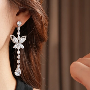 Close-up of elegant silver butterfly drop earring with sparkling zircon crystals on model