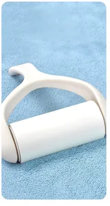 Close-up of a handheld lint roller with white handle on blue plush pet bathrobe fabric