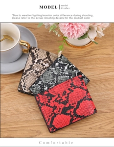 Close-up of snakeskin embossed leather wallets in red, grey and brown on a wooden desk