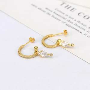 Detail of gold C-hoop earrings with pave white zircons and teardrop crystal pendants