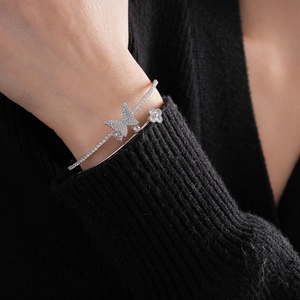 Detailed close-up of silver-tone double-layer bangle with zircon butterfly and clover charms