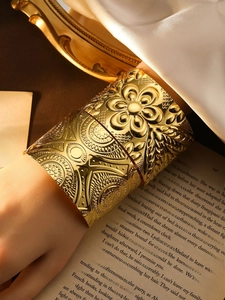 Makro-Detail des böhmischen goldenen breiten Armreifs mit geprägtem Blumenrelief