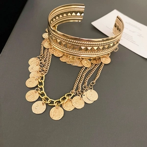 Detalle de cadenas doradas multicapa y colgantes de monedas en este brazalete de lujo