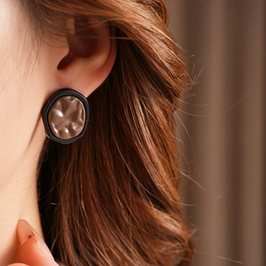 Macro view of irregular geometric earrings with brown lava texture and black border