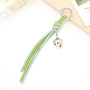 Detail of woven green and light blue leather keychain with silver heart pendant