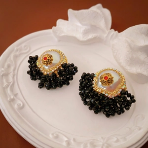 Detail of vintage baroque floral earrings with black beads and a central faux pearl