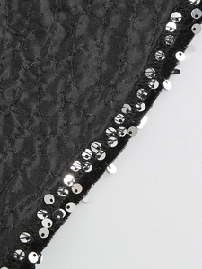 Detail of black dress featuring textured diamond pattern with silver sequins and velvet trim