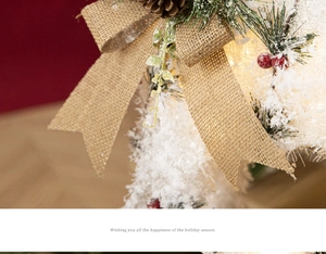 Detail der Weihnachtsdeko mit Leinenschleife, Zapfen und warmen Leuchtelementen