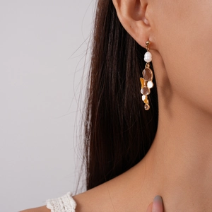 Detail of vintage irregular geometric earrings with amber resin and pearl on model