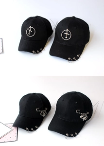 Close-up of black cotton baseball caps with silver rings and punk-style metal pin charms