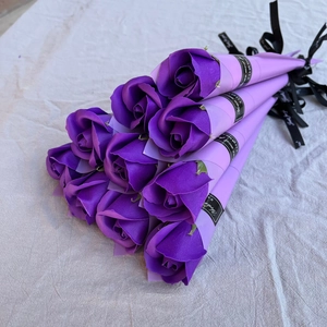 Eight purple soap roses individually wrapped with black ribbons on beige linen