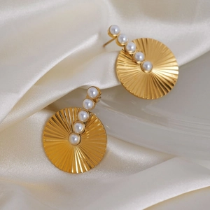 Chic gold hoop earrings with sunburst texture and five inlaid pearls on silk background