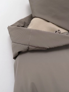 Close-up of stitched collar on gray-brown hooded jacket showing premium fabric texture
