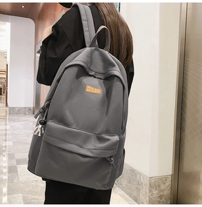 Detail of grey canvas backpack with astronaut charm and Coolboy leather tag on model