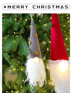 Detail of glowing Christmas gnomes with warm LED light hanging on a festive tree