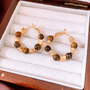 Detail of 18k gold plated tiger eye beaded hoop earrings in a wooden jewelry box