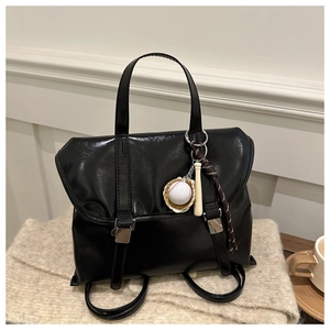 Dettaglio dello zaino vintage nero lucido con fibbie magnetiche e ciondoli sportivi