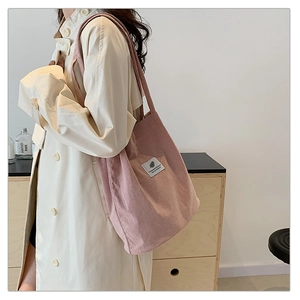 Detail of pink corduroy tote bag showing soft ribbed texture and minimalist brand patch