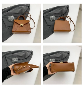 Detail view of brown crocodile texture handbag with gold hardware and protective base feet