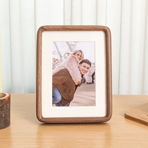 Solid walnut wood picture frame with rounded corners and white matting on wooden desk
