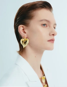Close-up of model wearing gold irregular white enamel calla lily earrings and necklace set