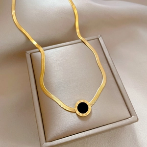 Macro detail of gold-plated snake chain and Roman numeral pendant on a jewelry box