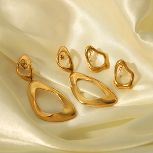 Golden irregular geometric earring set with pearls on luxurious beige silk fabric