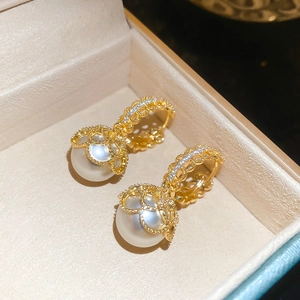 Macro detail of gold plated pearl earrings with zircon lace and vintage floral texture