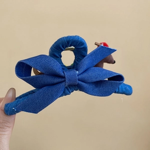 Vue détaillée d'une grande pince à cheveux avec nœud en denim marine et ourson en peluche