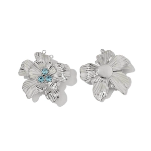 Detailed view of silver flower charms with blue stones and a smooth metallic back