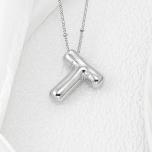 Macro view of polished silver puffy letter T pendant on a minimalist O-chain necklace