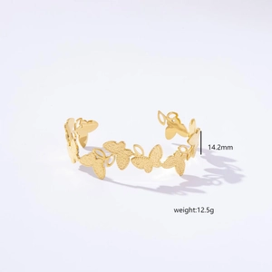 Detailed close-up showing the 14.2mm width and 12.5g weight of gold butterfly bangle