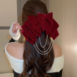 Close-up of red velvet bow hair clip with faux pearl fringe and glitter detail