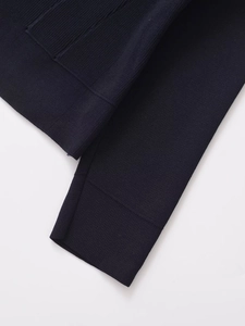 Macro shot of navy blue knitted fabric texture and ribbed cuff detail on women's cardigan