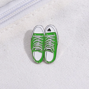 Detail of green canvas sneaker enamel pins with a black heart on a white canvas background