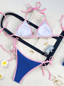 Flat lay of pink and blue string bikini set with beach accessories on white texture