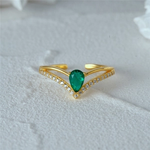 Macro shot of 925 silver V-shaped ring with green teardrop stone and gold finish