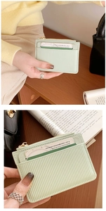Detail of light green textured card holder with multiple slots and zipper pocket in hand