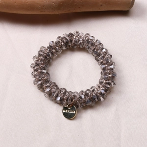 Close-up of grey faceted crystal beads and gold engraved metal charm on silk