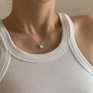 Detail view of shell pendant necklace with blue bead and gold chain on female neck