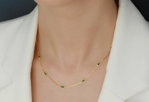 Close-up of elegant gold s925 silver necklace with emerald zircons on model neck