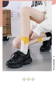 Detail of yellow and white gradient mid-calf socks paired with black sporty sneakers