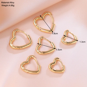 Three sizes of gold heart-shaped hoop earrings 1.8cm 1.5cm 1.3cm on a pink fabric